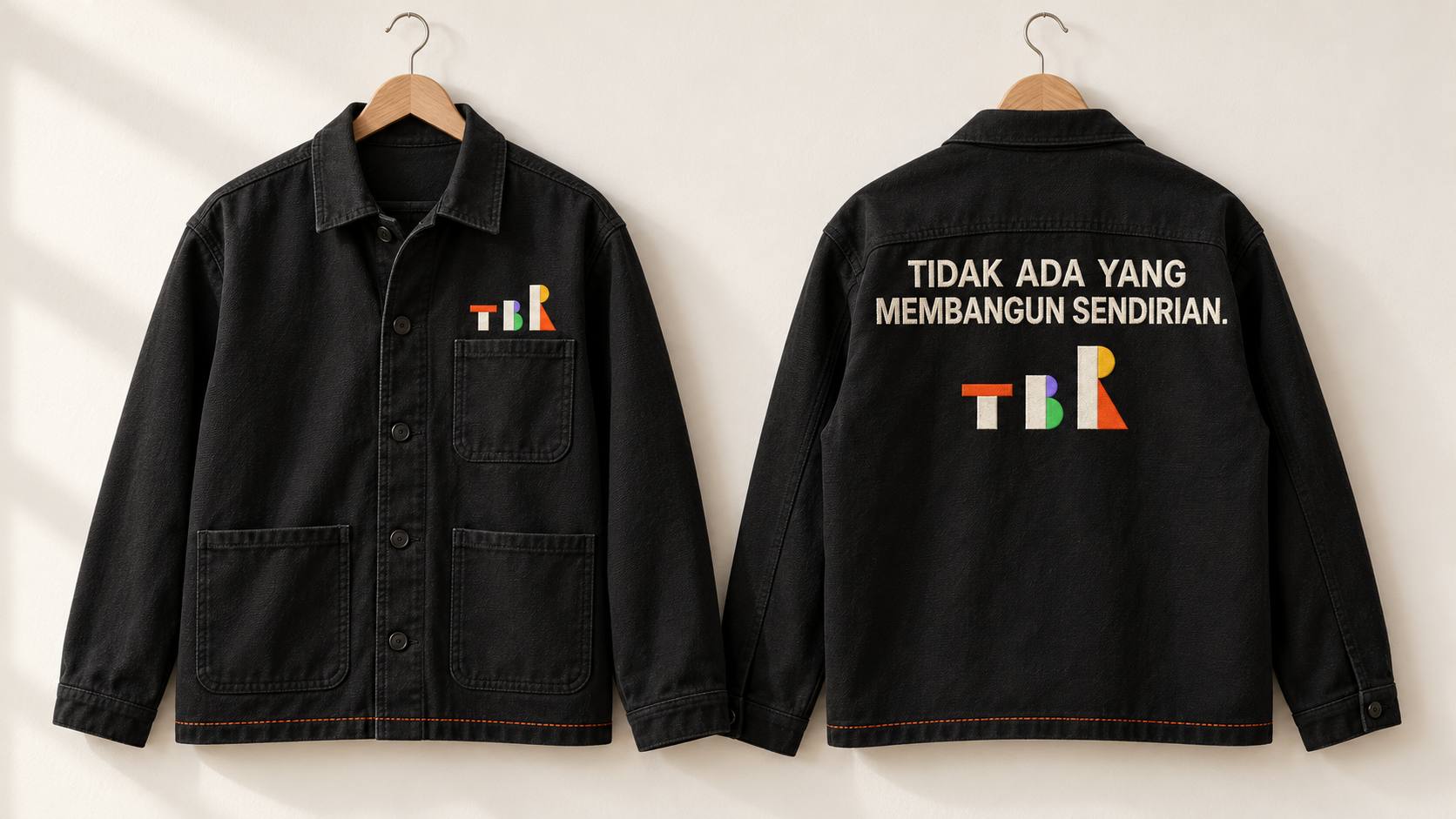 Jaket kerja hitam dengan logo TBR bordir di dada, dan bordir TIDAK ADA YANG MEMBANGUN SENDIRIAN di punggung.